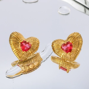 Macro detail of golden heart earrings with red gemstones and radial texture