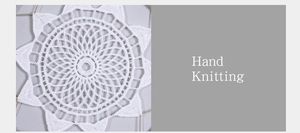 Close-up of white hand-knitted textile with intricate radial pattern and fringe details