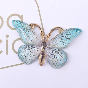 Macro detail of gradient blue and purple resin butterfly pendant with gold plated edges
