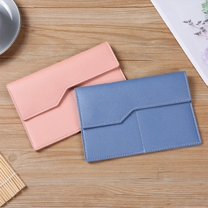 Detail of pink and blue textured PU leather envelope wallets with white stitching on wood