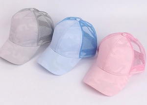 Detailed view of mesh ponytail baseball caps in grey, light blue, and pink camo