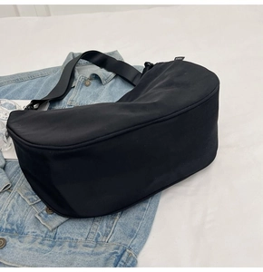 Close-up of black waterproof nylon dumpling bag on denim background with fashion label