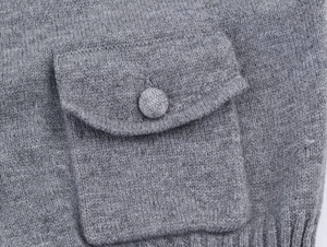 Détail d'un gilet gris en maille avec poche à bouton et texture d'ourlet côtelé