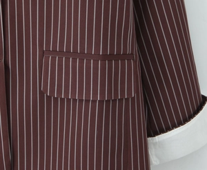 Detailed close-up of brown striped blazer featuring a flap pocket and white folded cuffs