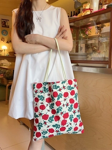 Sac fourre-tout en toile à motif de roses rouges porté par un mannequin au café