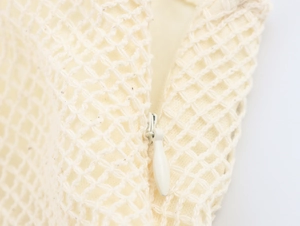 Makroaufnahme von cremefarbenem Häkelstrick mit unsichtbarem Reißverschlussdetail