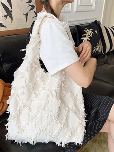 Large white canvas tote bag with bohemian fringe detail shown in a casual lifestyle setting