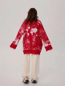 Detail of red oversized cardigan featuring a white world map pattern and distressed hem