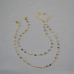 Close-up of minimalist gold necklaces with multi-colored natural stone beads and lobster clasp