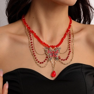 Détail du collier multicouche en perles rouges avec papillon en cristal et pendentif goutte