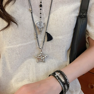 Détail du collier tissé multicouche et du bracelet en cuir avec charms cœur et croix