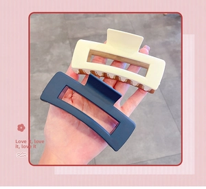 Detail of matte rectangular hollow hair claws in cream white and navy blue colors