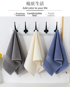 Detailed texture of thick cotton towels in grey, beige, and blue hanging on hooks