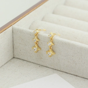 Détail des boucles d'oreilles pendantes triple étoile dorée avec zircons blancs brillants