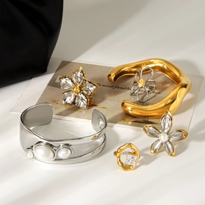 Artistic collection of pearl bracelet flower earrings and zircon ring on beige backdrop