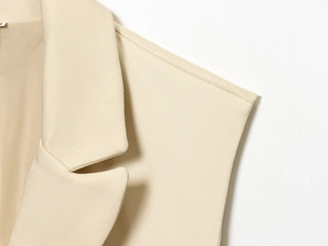 Détail macro du revers cranté et du tissu sergé sur un ensemble gilet sans manches beige