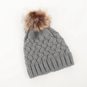 Detailed knit texture of a grey baby beanie with a fluffy brown faux fur pompom top