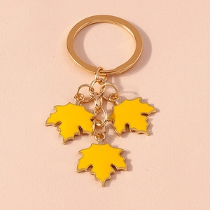 Detailed macro view of yellow enamel maple leaf charms on a golden metal keychain