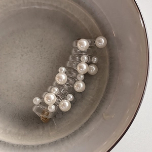 Transparent hair claw clip with elegant white faux pearls in a ceramic bowl