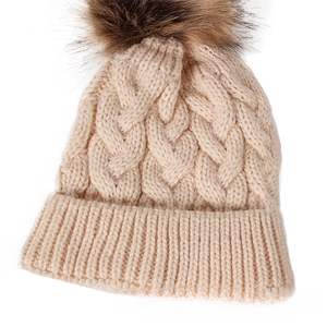 Close-up of thick cable knit texture and large faux fur pom-pom on the winter beanie