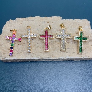 Detail of 18k gold plated cross pendants with colorful cubic zirconia on stone slab