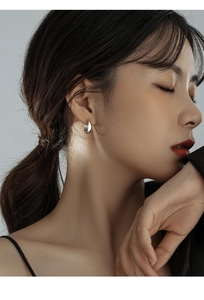 Close-up of a minimalist silver hoop earring worn by a model for a stylish look