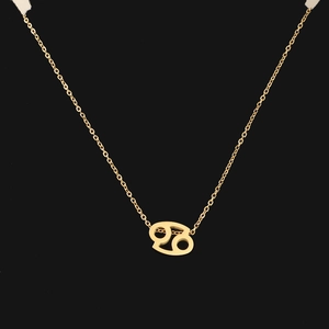 Macro detail of gold Cancer zodiac sign pendant on thin chain over black background