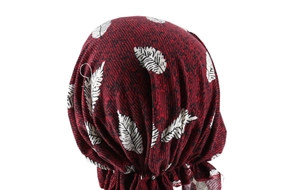 Close-up of red turban hat with white leaf patterns showing fabric texture and pleats