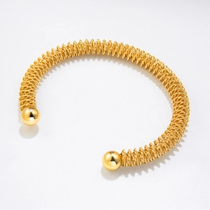 Detail of 18K gold plated stainless steel spring bracelet with polished metal spheres