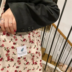 Detalle de bolso tote de pana floral con etiqueta tejida blanca y motivo de pluma