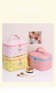 Three quilted checkerboard cosmetic bags with bow embroidery and top handles