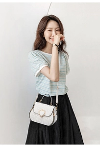 Detail of white pleated bucket bag with quilted heart-shaped metal buckle closure