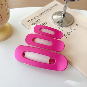 Detail of a matte rose red plastic hair clip with unique triple-layered cutout design