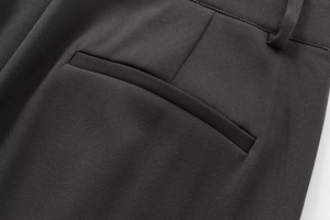 Détail de la poche arrière et des coutures sur un pantalon en sergé noir pour femme