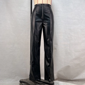 Close-up of black high-waisted faux leather pants featuring a front zipper and side slit hems