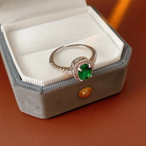 Detailed shot of an oval green zircon ring with sparkling diamonds in a velvet box