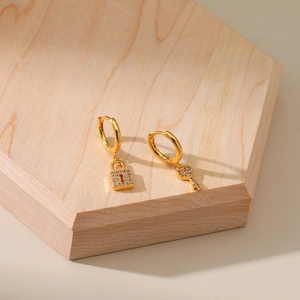 18K gold plated hoop earrings with zircon-paved lock and key pendants on a wooden stand