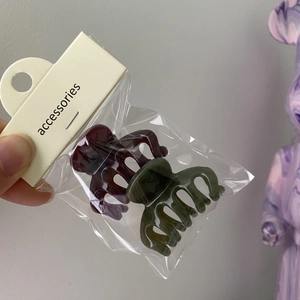 Detail view of dark red and army green jelly hair claws in clear polybag packaging