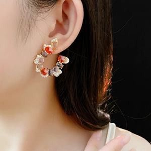 Close-up of elegant U-shaped earrings with colorful gemstones and sparkling zircons
