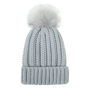 Detail of grey cable knit beanie featuring a large matching faux fur pompom on top