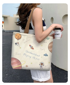 Outdoor shot of cream canvas tote bag with astronaut print and brown straps