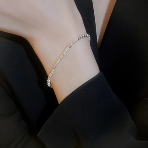 Macro shot of a faceted silver bead bracelet on a model wearing a black blazer