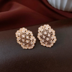 Detail view of oval hollow zircon stud earrings in rose gold on leather surface