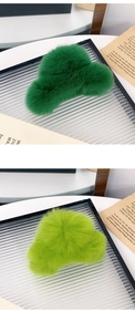 Detailed view of plush faux fur hair claws in dark green and light green on a tray