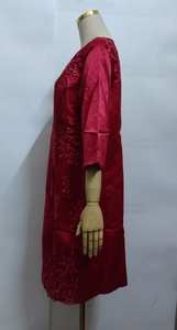 Detailed side view of red dress with intricate floral embroidery on wooden mannequin