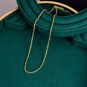 Detail showing golden bead chain necklace with lobster clasp on green velvet display
