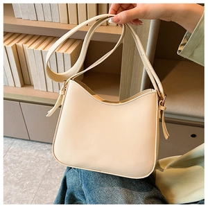Détail d'un sac d'épaule beige en demi-lune avec finition cuir lisse et boucle argent