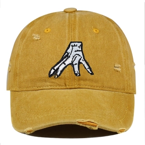 Close-up of vintage yellow washed cotton baseball cap with hand gesture embroidery and distressed details