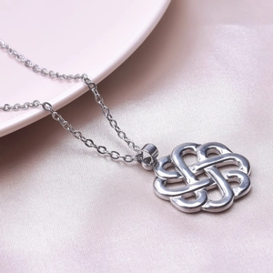 Macro shot of silver stainless steel Celtic witch knot necklace pendant on pink satin