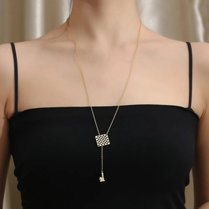 Detail of gold-plated long sweater necklace with checkered square and chess horse pendants